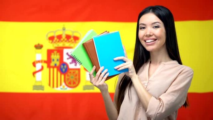亚洲女孩展示西班牙国旗背景下的字帖，学习语言