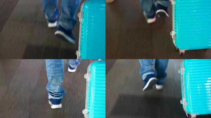 旅行者走路时的腿和拖着蓝色行李