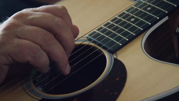 一个高加索人的手指拨动原声吉他的琴弦的特写镜头