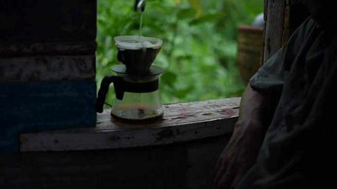 滴咖啡过程中，该男子将热水倒在老式窗户上的地面上。