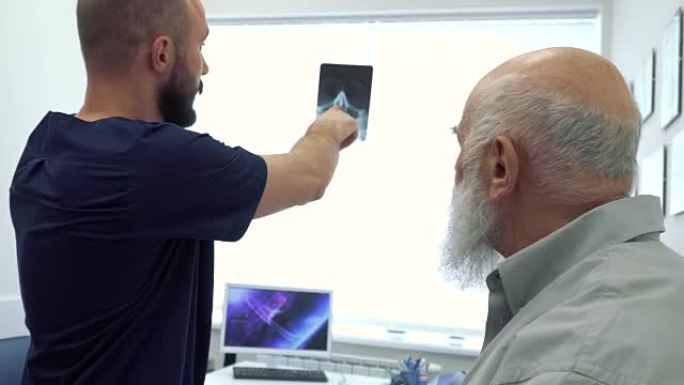 风湿病学家向一个成熟的男人展示射线照片