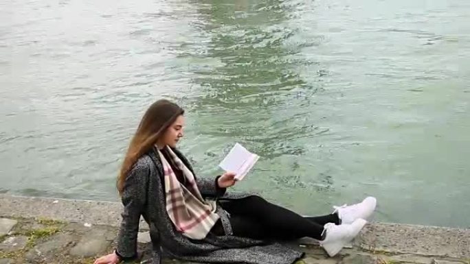 年轻女子在河沿岸阅读书籍
