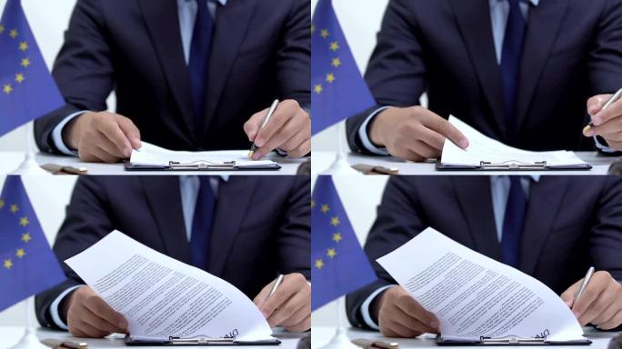 男性政治家聚精会神地阅读备忘录，桌上放着欧盟的旗帜
