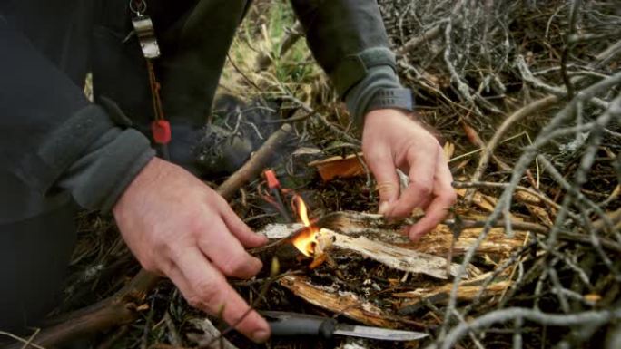 男性荒野生存专家在森林空地上点火
