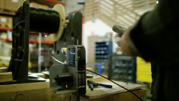 高加索人通过制造设施中的测量设备 (长度计数器) 拉动电线