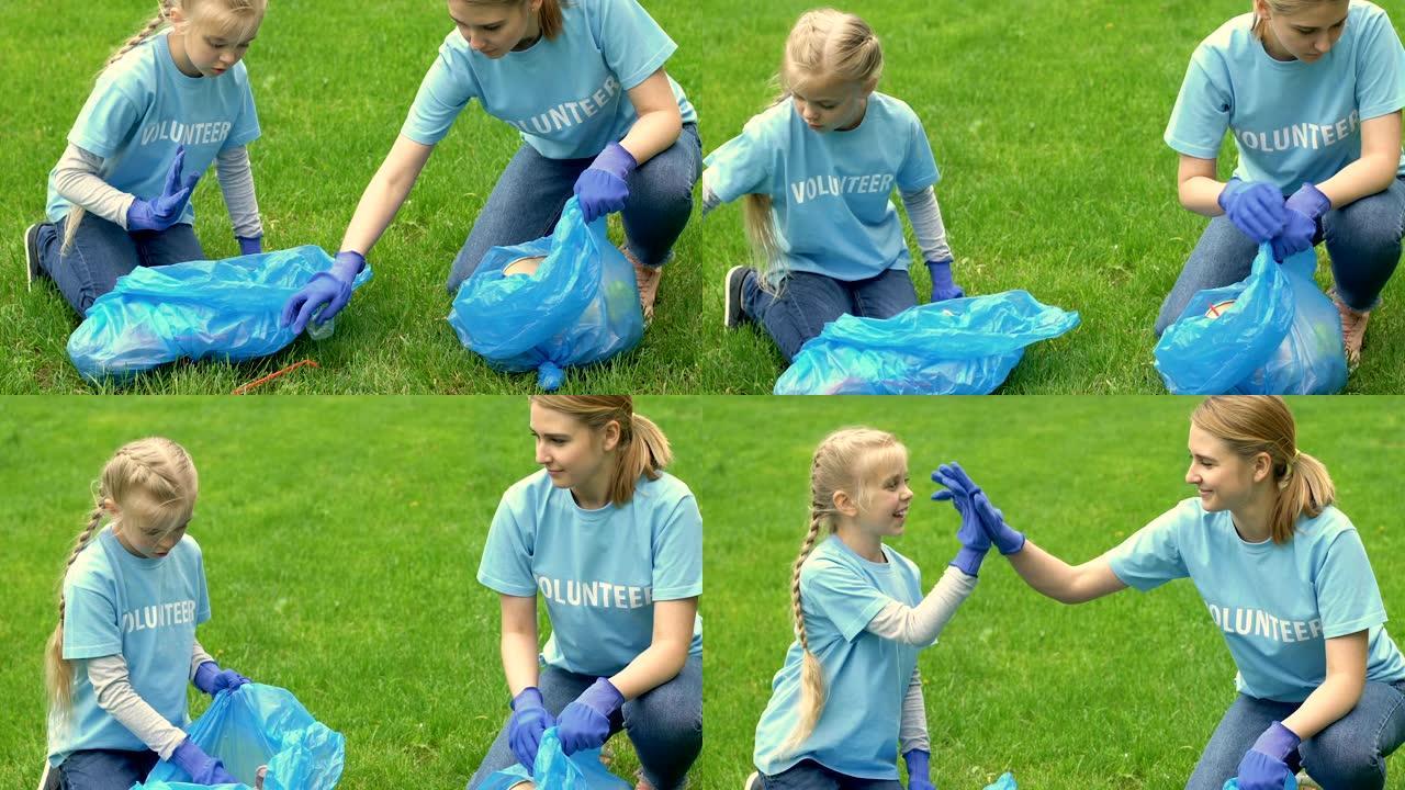 母亲和小女孩的志愿者在公园里收集垃圾，给高五