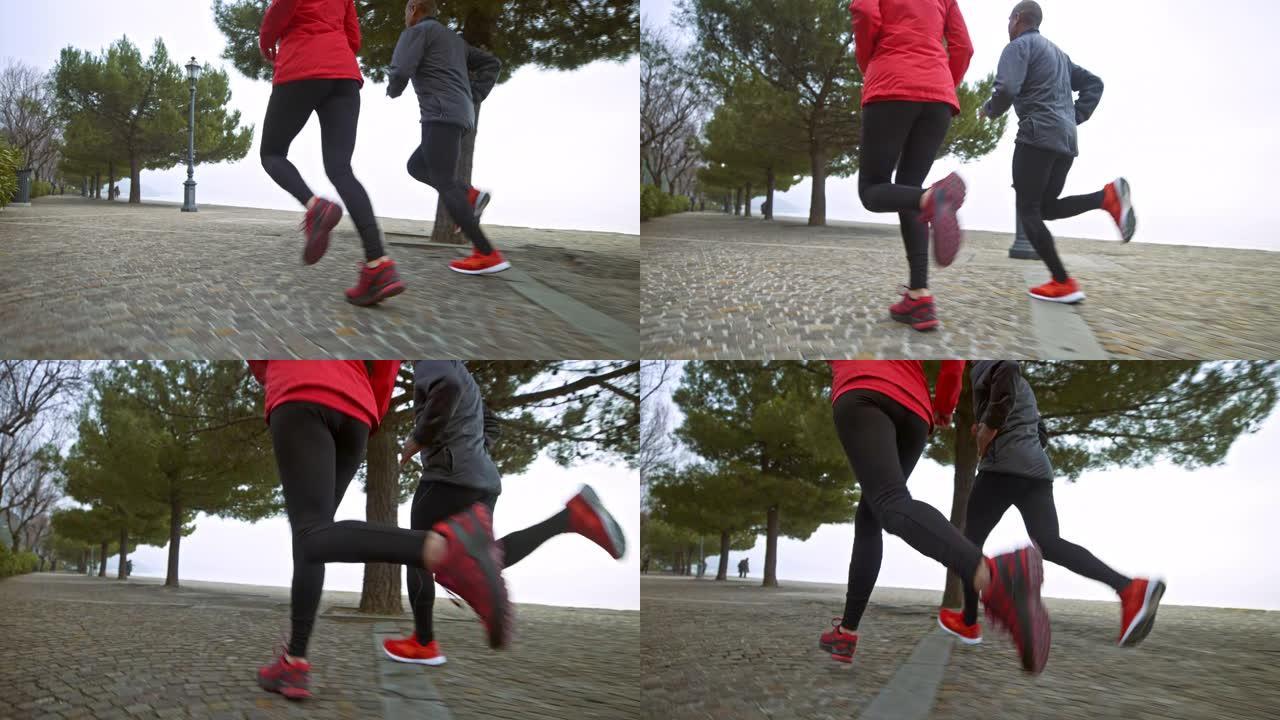 清晨，一名男女跑步者在海边的人行道上奔跑的SLO MO腿