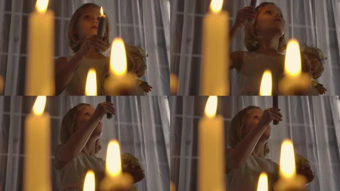 奇怪的高加索女孩拿着洋娃娃和蜡烛抬头的特写脸。晚上站在大窗前的烛光下的陌生孩子。恐惧，恐惧，奇怪。
