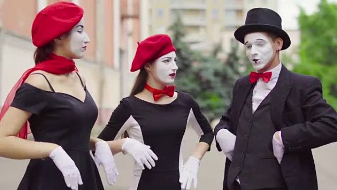 三个滑稽的哑剧演员在城市的街道上表演