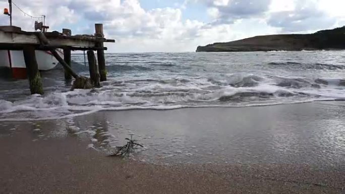 Waves in a cloudy day next to small pier in Seyrek