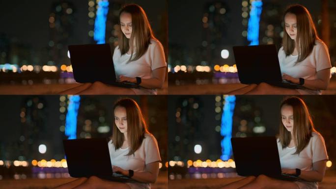 年轻的女孩设计师晚上在棕榈树下在外面的笔记本电脑上远程工作