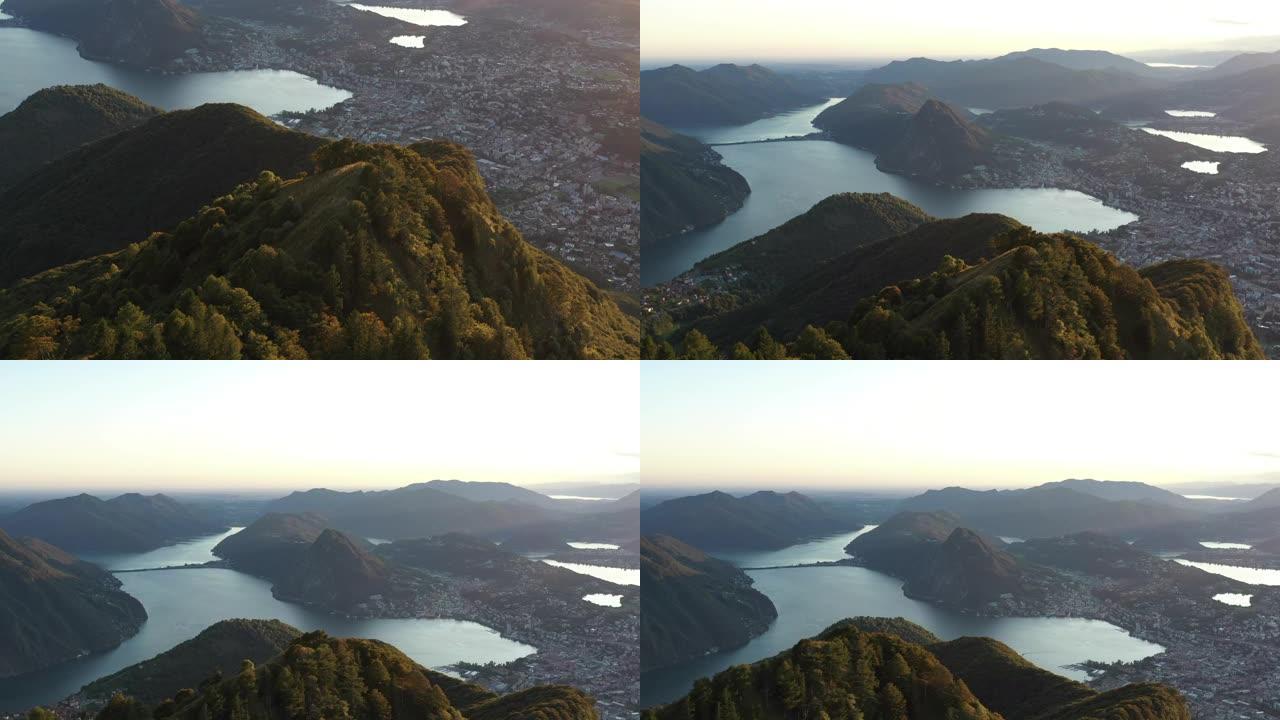日落时卢加诺湖和周围山脉的空中无人机视图