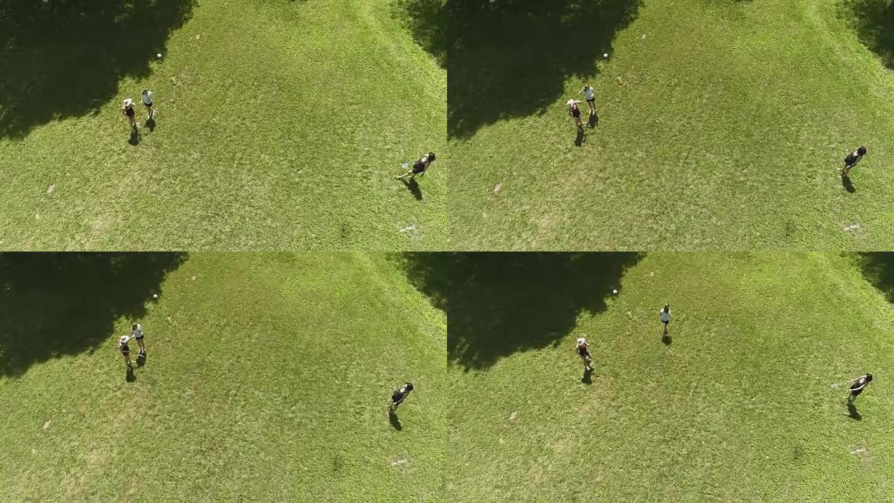 两个女人在草坪上打羽毛球。十几岁的女孩把一瓶水给他们中的一个。正上方俯视图，空中无人机视频