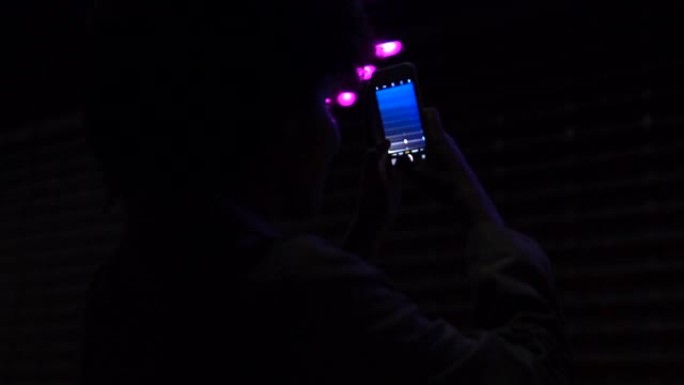 女孩在智能手机上拍摄led节目的剪影，夜间照明，假期