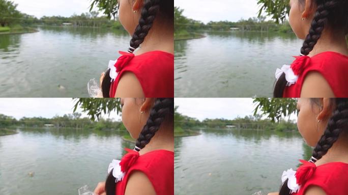 亚洲女孩在公园里喂鱼，慢动作
