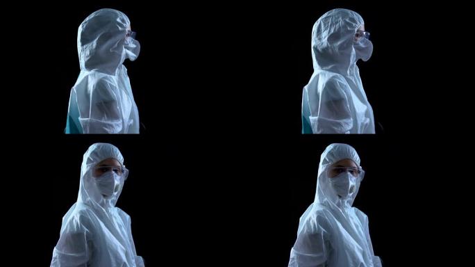穿着防护服和面罩的实验室工作人员在黑暗背景下转向相机