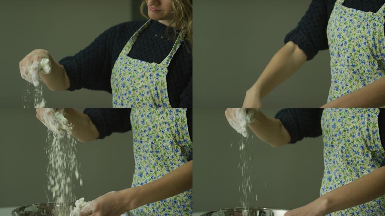 倾斜一名三十多岁的白人妇女的镜头，用手将大块黄油分解成面粉 (切成小块并混合)，在金属搅拌碗中制成面