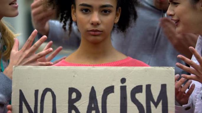 混血女孩举着“禁止种族歧视”的牌子，遭到人群的种族侮辱