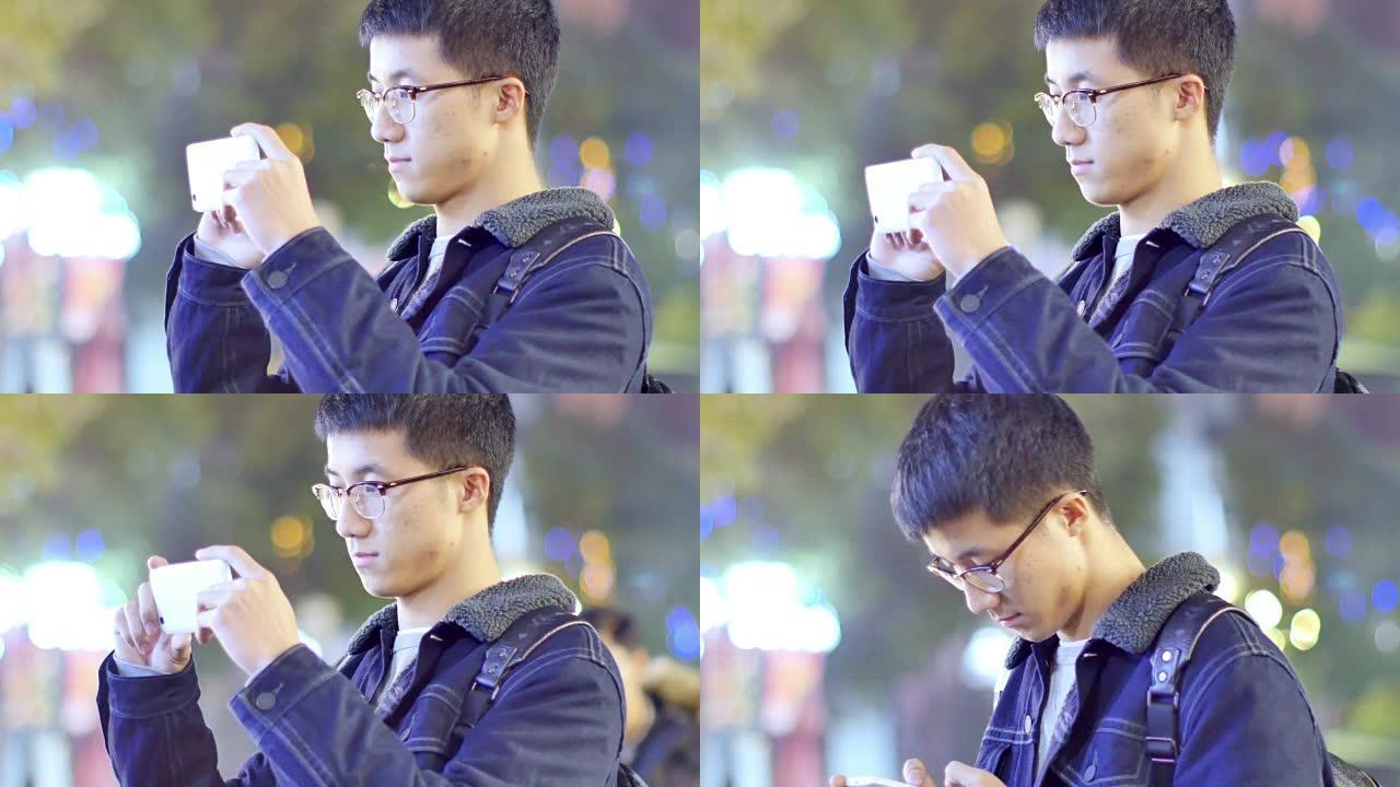 亚洲男子学生晚上在校园里手持手机