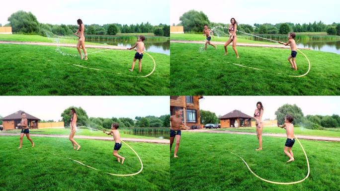 两个男孩和爸爸妈妈在自家后院玩，他们浑身湿透，慢镜头里笑着。幸福的家庭