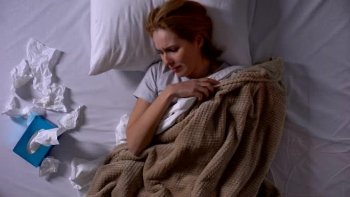 抑郁的女人躺在床上大声哭泣，抚摸着被单，痛不欲生