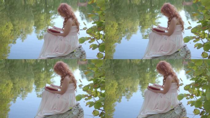 红发迷人的高加索女孩在夏季森林的湖岸上读暗红色的书