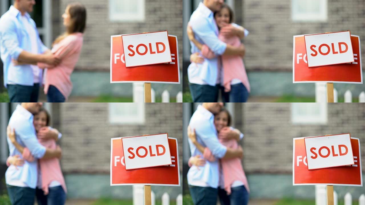 出售带有拥抱年轻夫妇的标志，背景，私有财产，搬迁