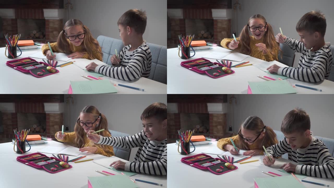 两个快乐的高加索孩子在练习本上微笑着写作。穿着条纹夹克的男孩和戴眼镜的女孩坐在学校的桌子旁做任务。摄