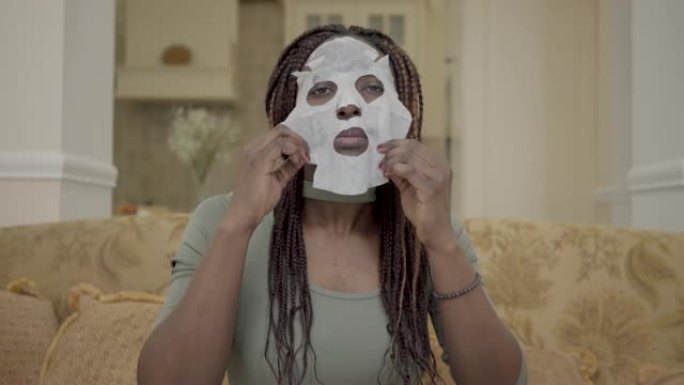 漂亮的非洲裔美国妇女的肖像，把保湿面膜在她的脸上在教练