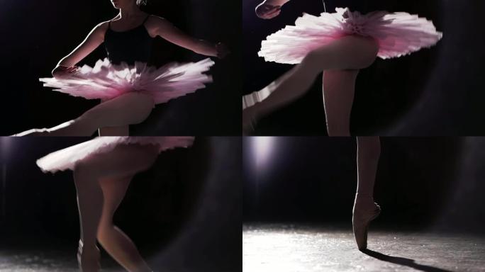 专业芭蕾舞演员在工作室的黑色背景下，在她的脚尖芭蕾舞鞋上跳舞。芭蕾舞演员展示了穿着芭蕾舞短裙和脚尖鞋