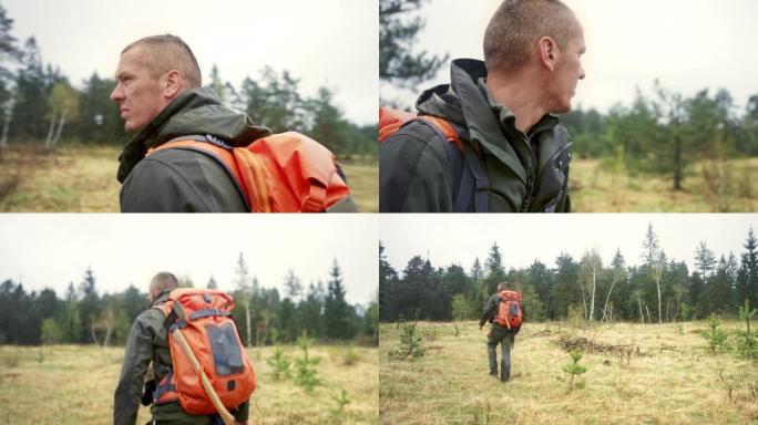 男性荒野生存专家检查他的周围环境并走向森林树木