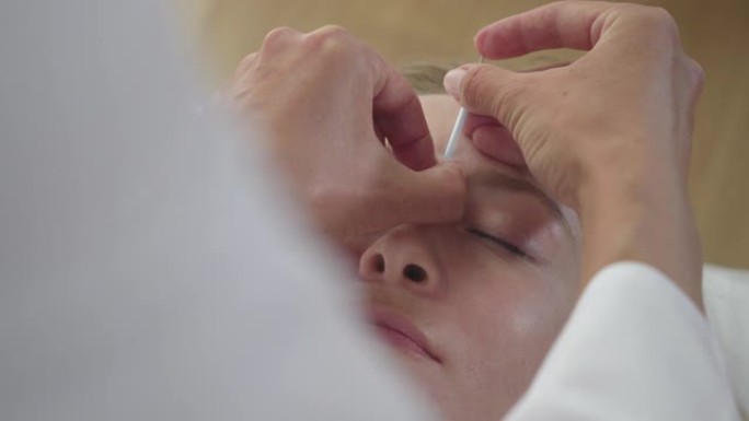 针灸师在年轻女子面前插入针头的极端特写。高加索医生治疗金发碧眼的亚洲女孩的头痛。替代医学，中医治疗。