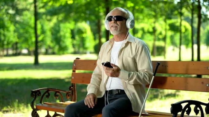 盲人老人戴着耳机听有声读物，手机中的语音信息