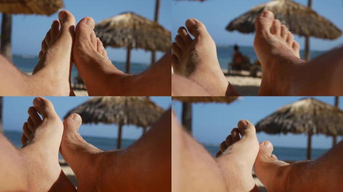 男人的脚在海滩上放松，POV
