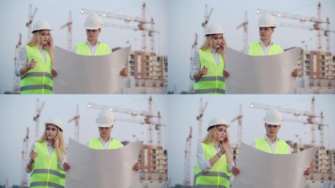 两名建筑工人戴着头盔和背心站在正在建造的建筑物的背景上，一名妇女与客户通电话