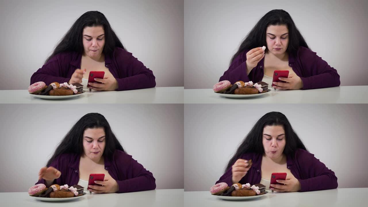 使用智能手机和吃甜食的集中高加索肥胖女孩的肖像。胖年轻女子有超重问题。不健康的节食，生活方式，肥胖。