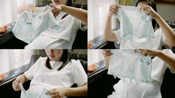 孕妇坐在沙发上为未来宝宝整理新衣服