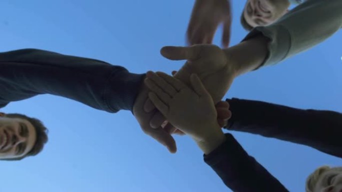 一群朋友把手放在一起，团队合作导致胜利，底部视图