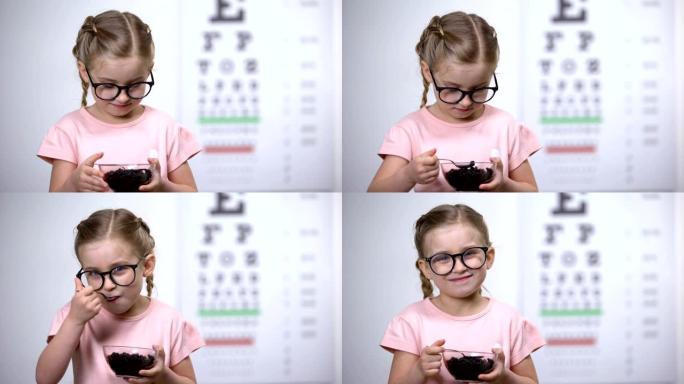 戴着眼镜的微笑女孩吃蓝莓，天然维生素改善视力