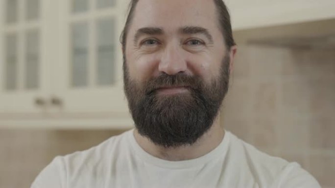 微笑的大胡子男人在镜头中近距离观察的肖像。