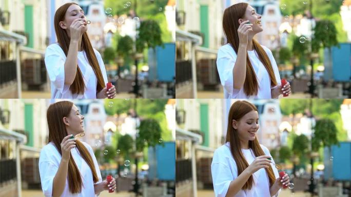 微笑的红发年轻女子在户外吹肥皂泡，在公园玩得开心