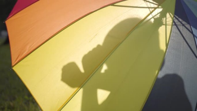 坐在雨伞后面，用手展示人物的无忧无虑的小孩的剪影。