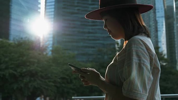 迷人的女人在新加坡城市发短信给智能手机