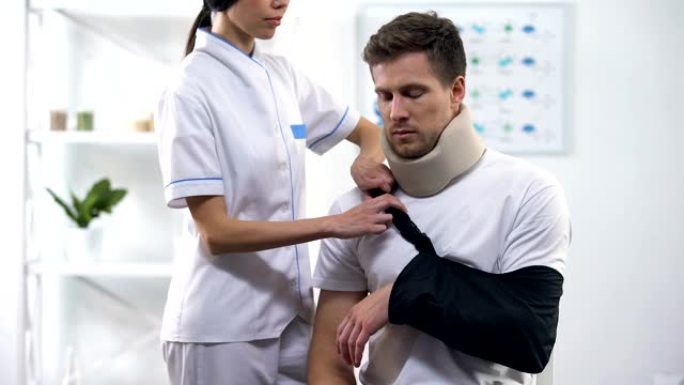 骨科医生将男性患者手臂吊带固定在正确的位置，创伤后康复