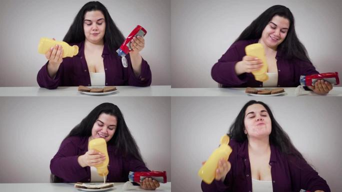 有趣的黑发高加索女人把番茄酱和蛋黄酱倒在面包上，微笑着。丰满开朗的女孩将敷料倒入嘴里，看着相机。不健