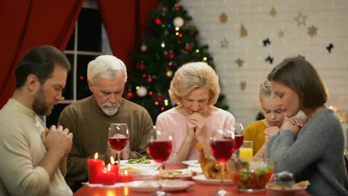传统家庭在圣诞节用餐前祈祷，信仰上帝，基督教