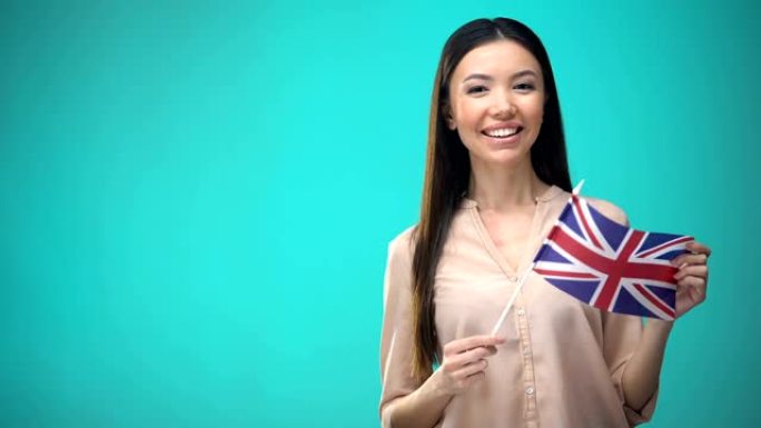 微笑的女人举着英国国旗，准备学习外语