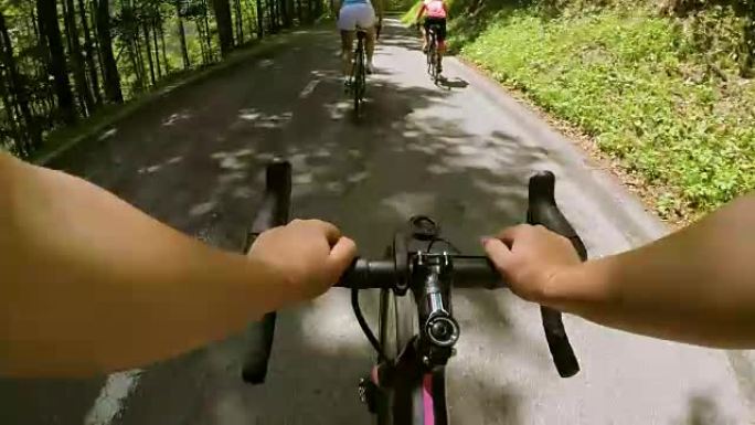 POV公路与两名女自行车手在阳光下沿着山路骑行