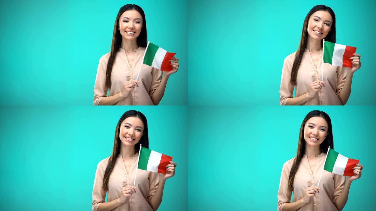 微笑的女士举着意大利国旗，准备学习外语，意大利学校