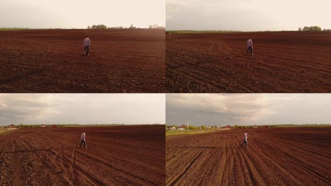 航拍无人机跟随一位农民走过一块土地的耕地。飞来飞去，跟随农民的俯视图